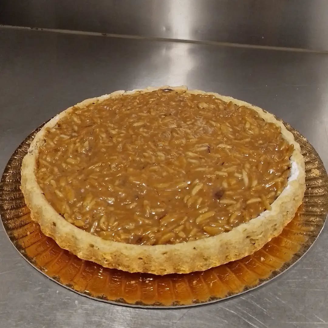 Tarte redonda coberta de amêndoa caramelizada, sobre papel dourado