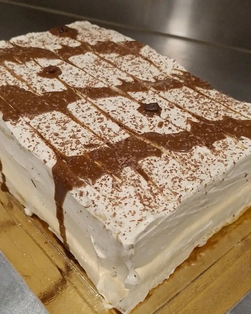 Bolo de café com cobertura branca e fios de chocolate, sobre base dourada