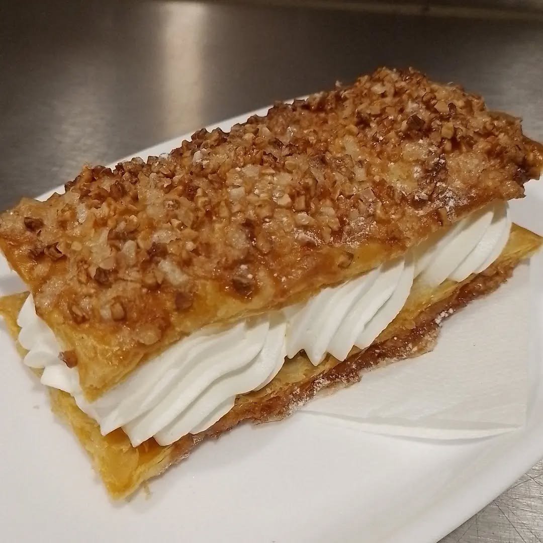 Folhado com natas e cobertura de frutos secos caramelizados, sobre um prato